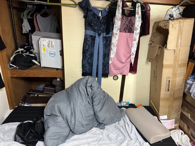 布団が敷きっぱなしでドレスが引っかけられている 押し入れの中は不用品が仕舞われている